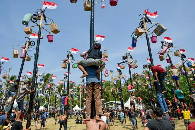 Participants attempt to climb greasy poles to collect prizes at the top during celebrations marking Indonesia's 78th Independence Day in Jakarta on August 17, 2023. (Photo by Bay Ismoyo/AFP Photo)