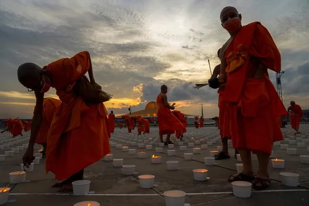 Buddhist monks wearing face masks light candles during Vesak Day, an annual celebration of Buddha's birth, enlightenment, and death at the Dhammakaya temple amid the coronavirus disease (COVID-19) pandemic in Pathum Thani province, Thailand, May 26, 2021. (Photo by Athit Perawongmetha/Reuters)