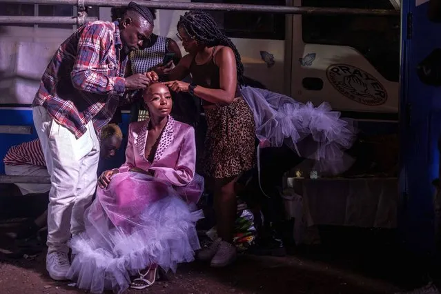 A model is helped by assistants to get a design ready at the backstage of the main show of the Kibera Fashion Week in the informal settlement of Kibera in Nairobi, on October 15, 2023. Kibera Fashion Week is a platform created from the community to redefine fashion and creativity while showcasing beauty and talent as a way to change the narrative about Nairobi's largest informal settlement. (Photo by Luis Tato/AFP Photo)