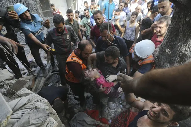 Palestinians rescue a child from under the rubble after Israeli airstrikes in Gaza City, Gaza Strip, Wednesday, October 18, 2023. (Photo by Abed Khaled/AP Photo)