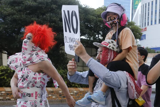 People march in Tokyo's Shinjuku shopping district Sunday, July 18, 2021, to protest against the Tokyo Olympics starting from July 23. They held signs that said No Olympics. (Photo by Yuri Kageyama/AP Photo)