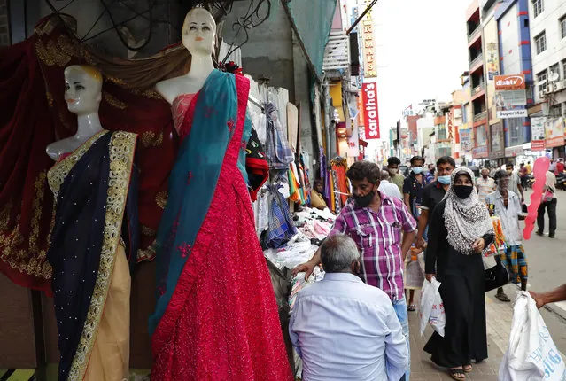 A Sri Lankan Muslim woman, right in black attire, walks in a busy street of Colombo, Sri Lanka, Saturday, March 13, 2021. Sri Lanka on Saturday announced plans to ban the wearing of burqas and said it would close more than 1,000 Islamic schools known as madrassas, citing national security. (Photo by Eranga Jayawardena/AP Photo)