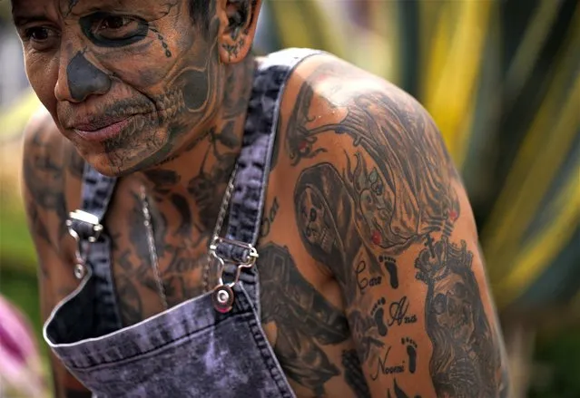 A devotee dons tattoos of “Nuestra Senora de la Santa Muerte”, or Our Lady of Holy Death, as he waits in line to enter her altar in Mexico City's Tepito neighborhood, Tuesday, November 1, 2022. La Santa Muerte is a cult image and folk saint, a personification of death, associated with healing, protection, and safe delivery to the afterlife by her devotees. (Photo by Fernando Llano/AP Photo)