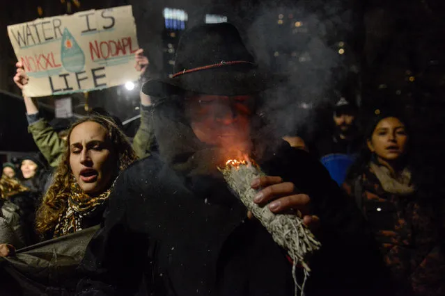 A man burns sage during a protest against President Donald Trump's executive order to allow the Keystone XL and Dakota Access pipelines in New York City, U.S. January 24, 2017. (Photo by Stephanie Keith/Reuters)