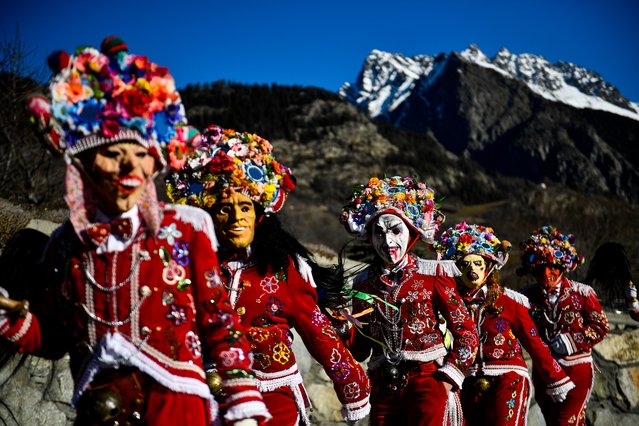 People dressed in colorful clothes and wearing scary wooden masks decorated with mirrors walks during the Napoleon-themed Coumba Freida Carnival on January 27, 2024 in Doues near Aosta, Italy. The typical costumes of this carnival recall the passage of the soldiers following Napoleon in May 1800. (Photo by Stefano Guidi/Getty Images)