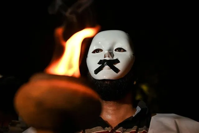 An Indian youth congress (IYC) member wearing a white mask with a taped mouth holds a torch during a protest in New Delhi on October 13, 2021, days after at least eight people died in an incident involving protesting farmers in Lakhimpur Kheri district of Uttar Pradesh state. (Photo by Sajjad Hussain/AFP Photo)