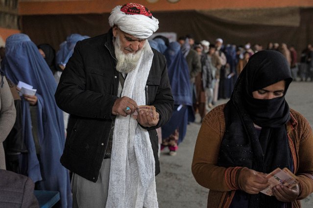 People count banknotes after receiving money from a World Food Program, in Kabul, Afghanistan, Saturday, November 20, 2021. With the U.N. warning millions are in near-famine conditions, the WFP has dramatically ramped up direct aid to families. (Photo by Petros Giannakouris/AP Photo)