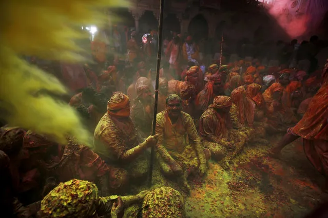 Hindu men from the village of Nangaon covered with colored powder sit on the floor during prayers at the Ladali or Radha temple before the procession for the Lathmar Holy festival, the legendary hometown of Radha, consort of Hindu God Krishna, in Barsana 115 kilometers ( 71 miles) from New Delhi, India, Sunday, March 9, 2014. (Photo by Altaf Qadri/AP Photo)