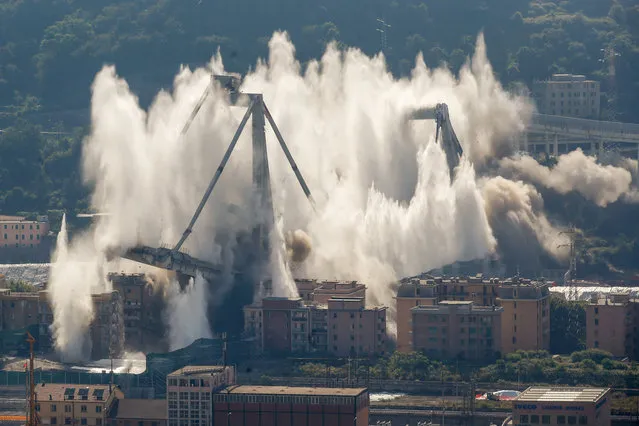 A cloud of dust rises as the remaining spans of the Morandi bridge are demolished in a planned expolosion, in Genoa, Italy, Friday, June 28, 2019. The spectacular planned explosion knocked down the remaining spans and supporting columns of the Italian bridge that collapsed last year, killing 43 people and some 3,500 people who live nearby had been evacuated as a precaution in the last hours; sirens sounded a final warning. (Photo by Antonio Calanni/AP Photo)