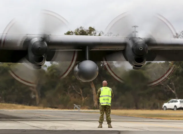 A RAAF ground crewmen stands in front of the moving propellors of a Royal Malaysian Air Force C-130 Hercules after it landed at RAAF Base Pearce to to help with the search for debris or wreckage of the missing Malaysia Airlines Flight MH370 in Perth, Australia, Saturday, March 29, 2014. (Photo by Rob Griffith/AP Photo)