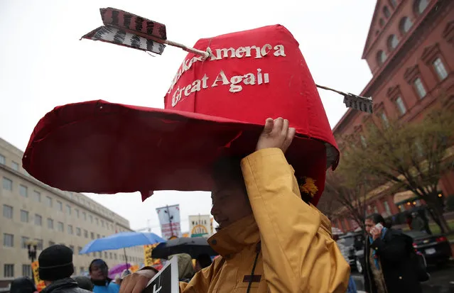 An activist put a giant “Make America Great Again” hat on her head outside the Army Corps of Engineers Office to protest against the Dakota Access Pipeline March 10, 2017 in Washington, DC. The Standing Rock Sioux Tribe held the event with a march to the White House to urge for halting the construction of the project. (Photo by Alex Wong/Getty Images)