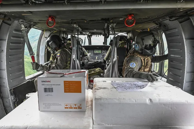 Colombian Air Force members fly on a Black Hawk helicopter as they transport a container with Sinovac vaccines against COVID-19 to be distributed in the rural areas of Antioquia, Colombia, on March 10, 2021. (Photo by Joaquin Sarmiento/AFP Photo)