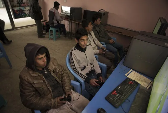 Boys play computer games at a market in Kabul March 2, 2014. (Photo by Morteza Nikoubazl/Reuters)
