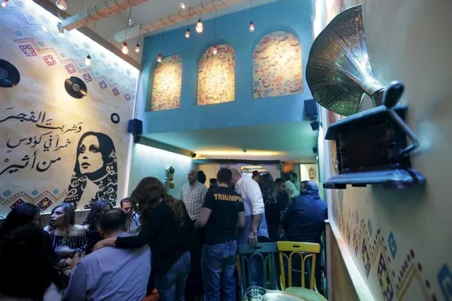 People sit at a newly opened pub near a stencil of Lebanese singer Fayrouz in Damascus, Syria, March 24, 2016. (Photo by Omar Sanadiki/Reuters)