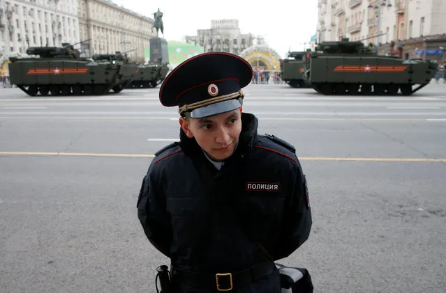 An Interior Ministry member stands guard as Russian military vehicles are parked in Tverskaya street before moving towards Red Square for a rehearsal for the Victory Day parade, marking the anniversary of the victory over Nazi Germany in World War Two, in central Moscow, Russia, April 28, 2016. (Photo by Maxim Zmeyev/Reuters)