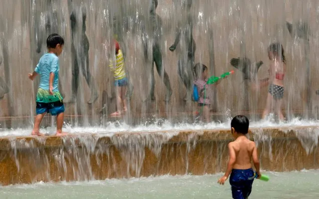 Children cool off in a water fountain at a park in Tokyo on July 31, 2019. (Photo by Kazuhiro Nogi/AFP Photo)