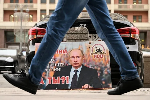 A placard featuring an image of Russian President Vladimir Putin and reading “We are with him for the sovereignty of Russia! And you?” is seen left in front of the Russian State Duma building in central Moscow on February 24, 2022. (Photo by Kirill Kudryavtsev/AFP Photo)