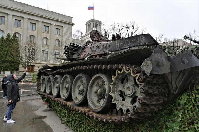 A woman takes a picture of a Russian T-72 tank destroyed in Ukraine placed in front of Russia's embassy in Berlin on February 24, 2023, on the first anniversary of the invasion of Ukraine. The wrecked tank was placed as an art installation by the “Berlin Story Bunker” group in front of the Russian embassy as “a symbol of Russia's downfall”. (Photo by ohn MacDougall/AFP Photo)