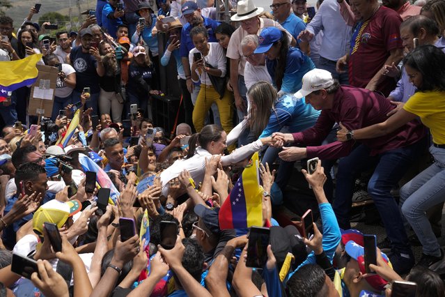 Venezuelan opposition leader Maria Corina Machado is lifted onto the stage as she arrives to help launch the campaign for presidential candidate Edmundo Gonzalez Urrutia, in La Victoria, Venezuela, May 18, 2024. (Photo by Ariana Cubillos/AP Photo)