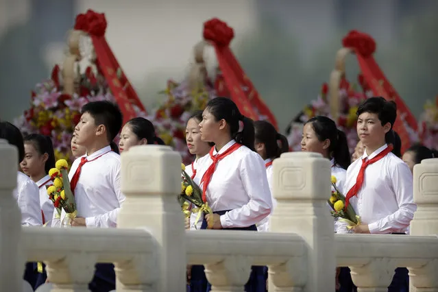 Schoolchildren carry flowers as they walk past floral wreaths at the Monument to the People's Heroes during a ceremony to mark Martyr's Day at Tiananmen Square in Beijing, Monday, September 30, 2019, ahead of a massive celebration of the People's Republic's 70th anniversary. (Photo by Mark Schiefelbein/AP Photo/Pool)