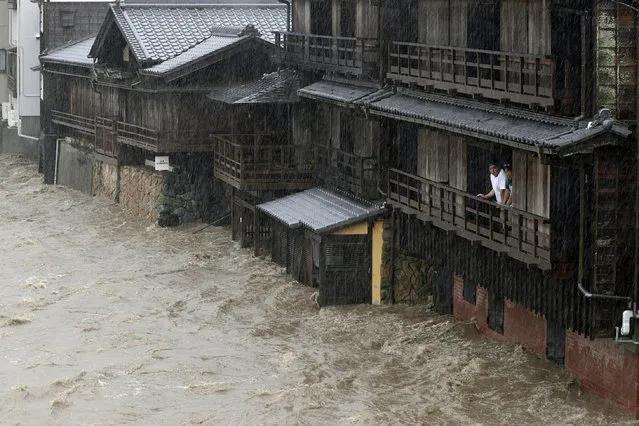 People watch the Isuzu River swollen by Typhoon Hagibis, in Ise, central Japan Saturday, October 12, 2019. Tokyo and surrounding areas braced for a powerful typhoon forecast as the worst in six decades, with streets and trains stations unusually quiet Saturday as rain poured over the city. (Photo by Kyodo News via AP Photo)