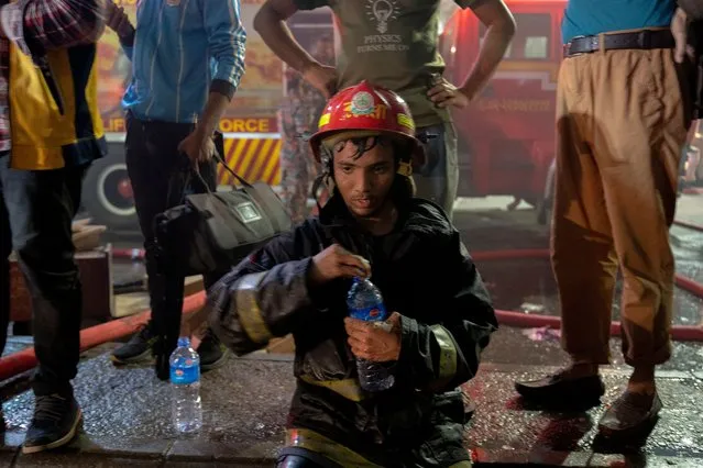 A firefighter drinks water after extinguishing the fire in Dhaka, Bangladesh on February 22, 2022. A fire broke out at Nilkhet book market, the largest book market. The fire gutted around 25 bookshops resulting in thousands of burnt books. The fire fighters doused the fire after about an hour. (Photo by Rizwan Hasan/Pacific Press/Rex Features/Shutterstock)