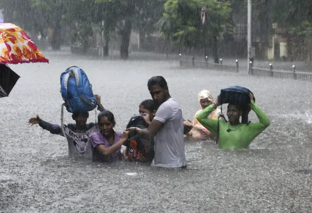 In this September 4, 2019, file photo, people hold hands and navigate their way through a flooded street as it rains in Mumbai, India. The number of people threatened by climate change-triggered flooding is about three times higher than previously thought, a new study says. But it's not because of more water. It's because the land, especially in Asia and the developing world, is several feet lower than what space-based radar has calculated, according to a study in the journal Nature Communications Tuesday, Oct. 29. (Photo by Rajanish Kakade/AP Photo/File)