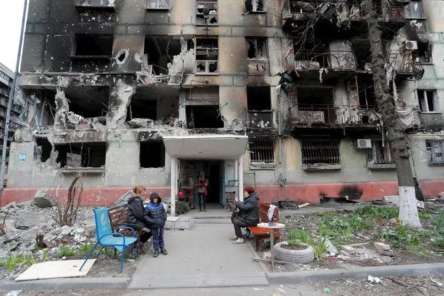 Local residents gather outside a residential building heavily damaged during Ukraine-Russia conflict in the southern port city of Mariupol, Ukraine on April 21, 2022. (Photo by Alexander Ermochenko/Reuters)