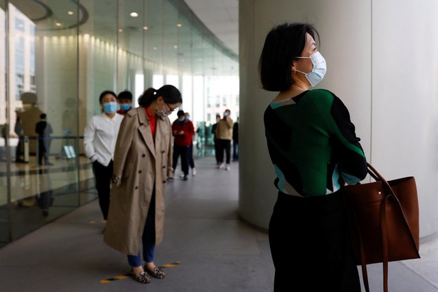 People line up to take nucleic acid tests at a makeshift testing site in an office complex following the coronavirus disease (COVID-19) outbreak in Beijing, China on April 26, 2022. (Photo by Carlos Garcia Rawlins/Reuters)
