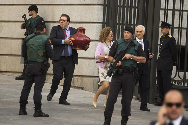 The king's crown is being carried under tight security before Spain’s newly crowned King Felipe VI arrives at the Parliament in Madrid, Spain, Thursday, June 19, 2014. Felipe is being formally proclaimed monarch Thursday after 76-year-old King Juan Carlos abdicated. Felipe was to swear an oath at a ceremony with lawmakers in Parliament in front of Spain's 18th-century crown and 17th-century scepter. (Photo by Andres Kudacki/AP Photo)