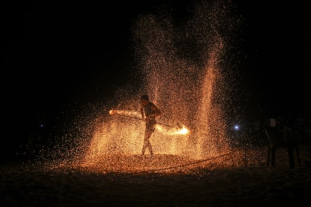 A fire dancer performs during a show for tourists on Batu Ferringhi Beach on Penang Island, Malaysia, Thursday, July 11, 2024. (Photo by Binsar Bakkara/AP Photo)