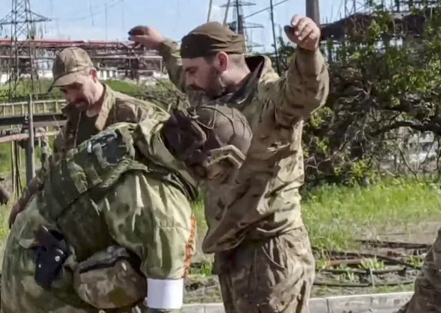 A handout still image taken from a handout video made available by the Russian Defence Ministry's press service shows Russian servicemen frisk Ukrainian servicemen as they are being evacuated from the besieged Azovstal steel plant in Mariupol, Ukraine, 17 May 2022. A total of 265 Ukrainian militants, including 51 seriously wounded, have laid down arms and surrendered to Russian forces, the Russian Ministry of Defence said on 17 May 2022. Those in need of medical assistance were sent for treatment to a hospital in Novoazovsk, the ministry states further. Russian President Putin on 21 April 2022 ordered his Defence Minister to not storm but to blockade the plant where a number of Ukrainian fighters were holding out. On 24 February, Russian troops invaded Ukrainian territory starting a conflict that has provoked destruction and a humanitarian crisis. According to the UNHCR, more than six million refugees have fled Ukraine, and a further 7.7 million people have been displaced internally within Ukraine since. (Photo by Russian Defence Ministry Press Service/EPA/EFE)