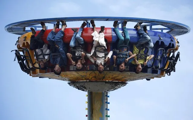 Pakistani youngsters react while taking a ride at a park in Rawalpindi, Pakistan, Tuesday, July 21, 2015. (Photo by Anjum Naveed/AP Photo)