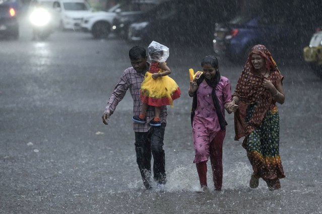 A family run as they cross a street during heavy rain in Hyderabad, India, Friday, September 6, 2024. (Photo by Mahesh Kumar A./AP Photo)