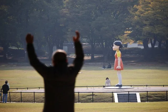 A man stretches as he looks at a giant doll named “Younghee” from Netflix series “Squid Game” on display at a park in Seoul, South Korea, October 26, 2021. (Photo by Kim Hong-Ji/Reuters)