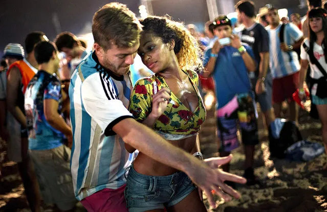 A woman from Brazil and a man from Argentina dance samba at the World Cup Fan Fest 2014, on Copacabana beach, in Rio de Janeiro, Brazil, Wednesday, July 9, 2014. The flood of foreign football fans, the vast majority of them men, has been a boon for the single ladies of Brazil, where a demographic imbalance means women outnumber men by more than 4 million nationally. (Photo by Silvia Izquierdo/AP Photo)