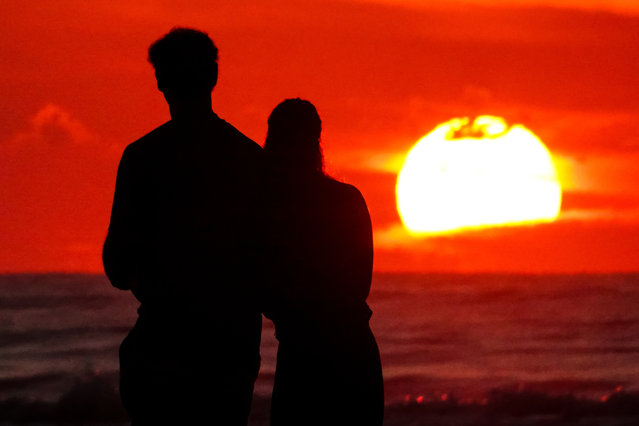 A couple, silhouetted by the sunrise stop to watch on the beach at Wild Dunes resort, October 7, 2024 in Isle of Palms, South Carolina. (Photo by Richard Ellis/ZUMA Press Wire/Rex Features/Shutterstock)