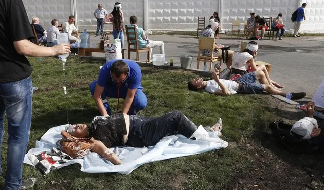 Paramedics treat injured passengers on a grass verge as several subway cars on a metro train derailed in Moscow, on July 15, 2014. (Photo by Mikhail Japaridze/AFP Photo)