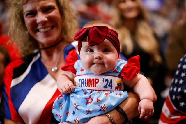 A woman holds a child wearing clothes in support of Republican presidential nominee and former U.S. President Donald Trump at his campaign rally in Rocky Mount, North Carolina on October 30, 2024. (Photo by Brendan McDermid/Reuters)