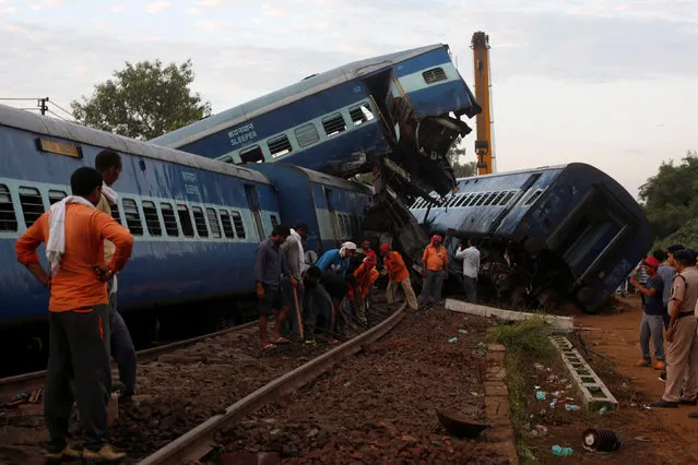Railway workers repair the tracks next to derailed coaches of a passenger train at the site of an accident in Khatauli, in the northern state of Uttar Pradesh, India August 20, 2017. (Photo by Adnan Abidi/Reuters)