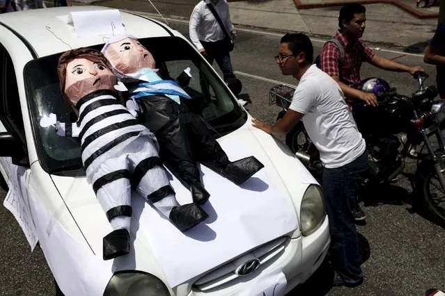 A cab driver looks at pinatas depicting former Vice President Roxana Baldetti (L) and Guatemalan President Otto Perez Molina during a demonstration demanding the resignation of  Perez Molina in Guatemala City, Guatemala, August 27, 2015. Baldetti will be held in jail throughout her trial over an alleged customs racket, a judge ruled on Wednesday. (Photo by Jose Cabezas/Reuters)