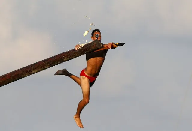 A competitor grabs the final flag as he falls off the “gostra”, a pole covered in grease, during the celebrations for the religious feast of St Julian, patron of the town of St Julian's, outside Valletta, August 30, 2015. (Photo by Darrin Zammit Lupi/Reuters)