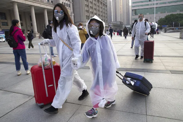 Passengers wearing face masks and rain coats to protect against the spread of new coronavirus walk outside of Hankou train station after of the resumption of train services in Wuhan in central China's Hubei Province, Wednesday, April 8, 2020. After 11 weeks of lockdown, the first train departed Wednesday morning from a re-opened Wuhan, the origin point for the coronavirus pandemic, as residents once again were allowed to travel in and out of the sprawling central Chinese city. (Photo by Ng Han Guan/AP Photo)
