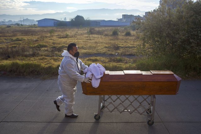 A man pushes the remains of his relative away from the morgue to take home in Quetzaltenango, Guatemala, Monday, December 20, 2021. A dozen people were slain Saturday in Chiquix, a village that has been involved in a years-long territorial dispute over water and land access with a nearby town, police said. (Photo by Oliver de Ros/AP Photo)