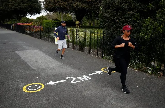 Two people jog past a social distance marker, as the spread of the coronavirus disease (COVID-19) continues, Dublin, Republic of Ireland, April 21, 2020. (Photo by Jason Cairnduff/Reuters)