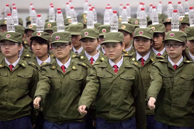 Students in military uniforms balance bottles of water on their heads as they practice goose-stepping marching during a military training session at a college in Zhengzhou, Henan province September 17, 2014. (Photo by Reuters/Stringer)