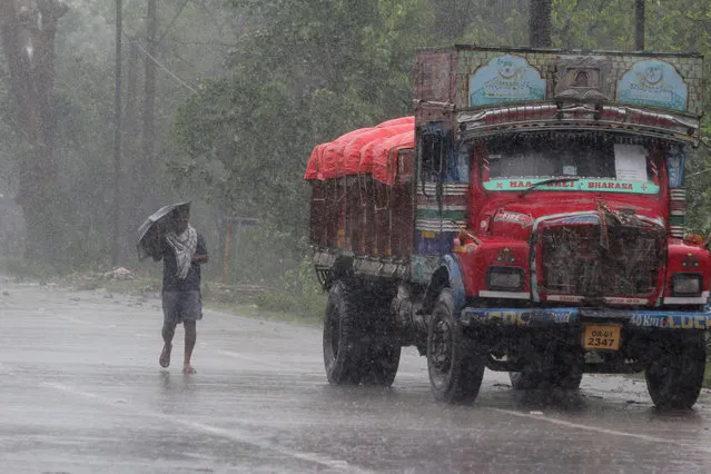 A man walks in the rain ahead of Cyclone Amphan landfall, at Bhadrak district, in the eastern Indian state of Orissa, Wednesday, May 20, 2020. A strong cyclone blew heavy rains and strong winds into coastal India and Bangladesh on Wednesday after more than 2.6 million people were moved to shelters in a frantic evacuation made more challenging by coronavirus. (Photo by AP Photo/Stringer)