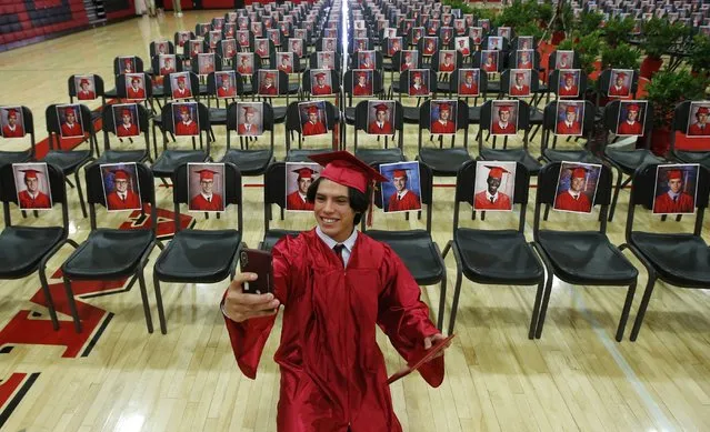 Paul Santiago Kelley, a graduating senior at Brophy College Preparatory, smiles as he takes a selfie as he celebrates Diploma Days with photos of all his fellow classmates after getting his diploma, due to the coronavirus Thursday, May 28, 2020, in Phoenix. The graduating Class of 2020 crossed the stage to graduate over a several-day period for social-distancing protocols. (Photo by Ross D. Franklin/AP Photo)