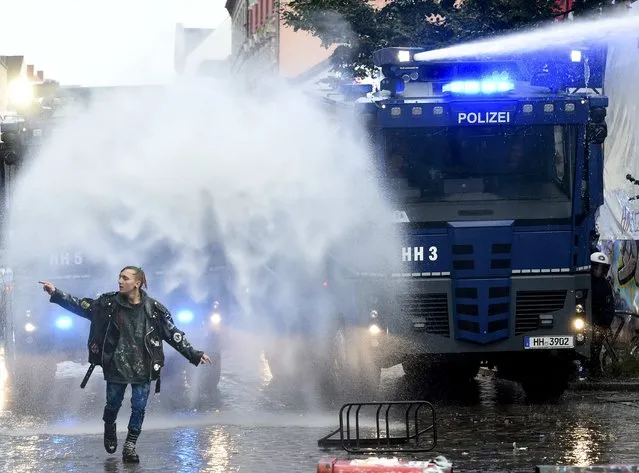 A left-wing protestor walks in front of police water cannons during a demonstration against a Nazi demonstration, which was forbidden by authorities, in Hamburg's Schulterblatt street in Schanzenviertel district, September 12, 2015. More than 10000 people demonstrate against the planned Nazi rally. (Photo by Fabian Bimmer/Reuters)