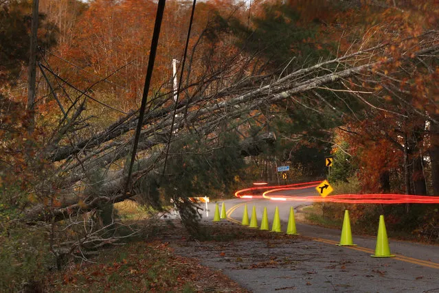 A car leaves a trail of light as it passes under power lines weighed down by toppled trees in Freeport, Maine, Tuesday, October 31, 2017. Utility crews scrambled to restore power throughout New England on Tuesday, one day after a severe storm packing hurricane-force wind gusts and torrential rain. (Photo by Robert F. Bukaty/AP Photo)